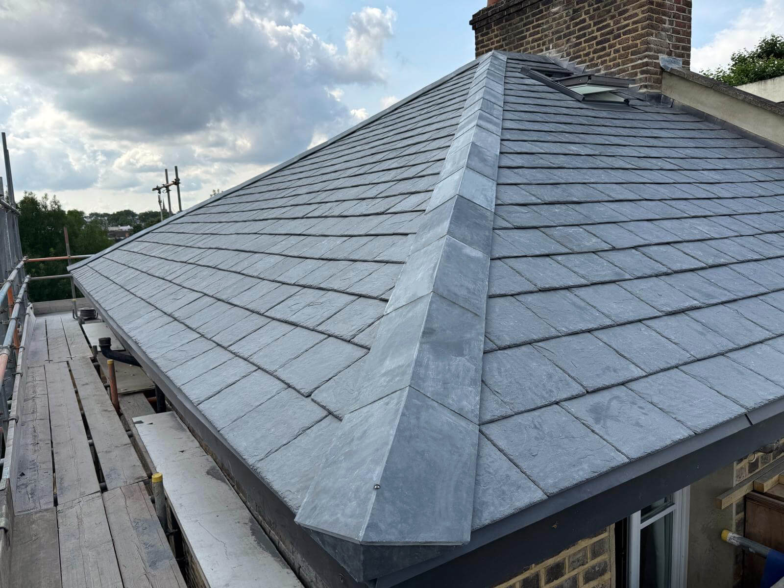 Newly installed graphite ArmouredSlate roof on a building with a cloudy sky in the background.
