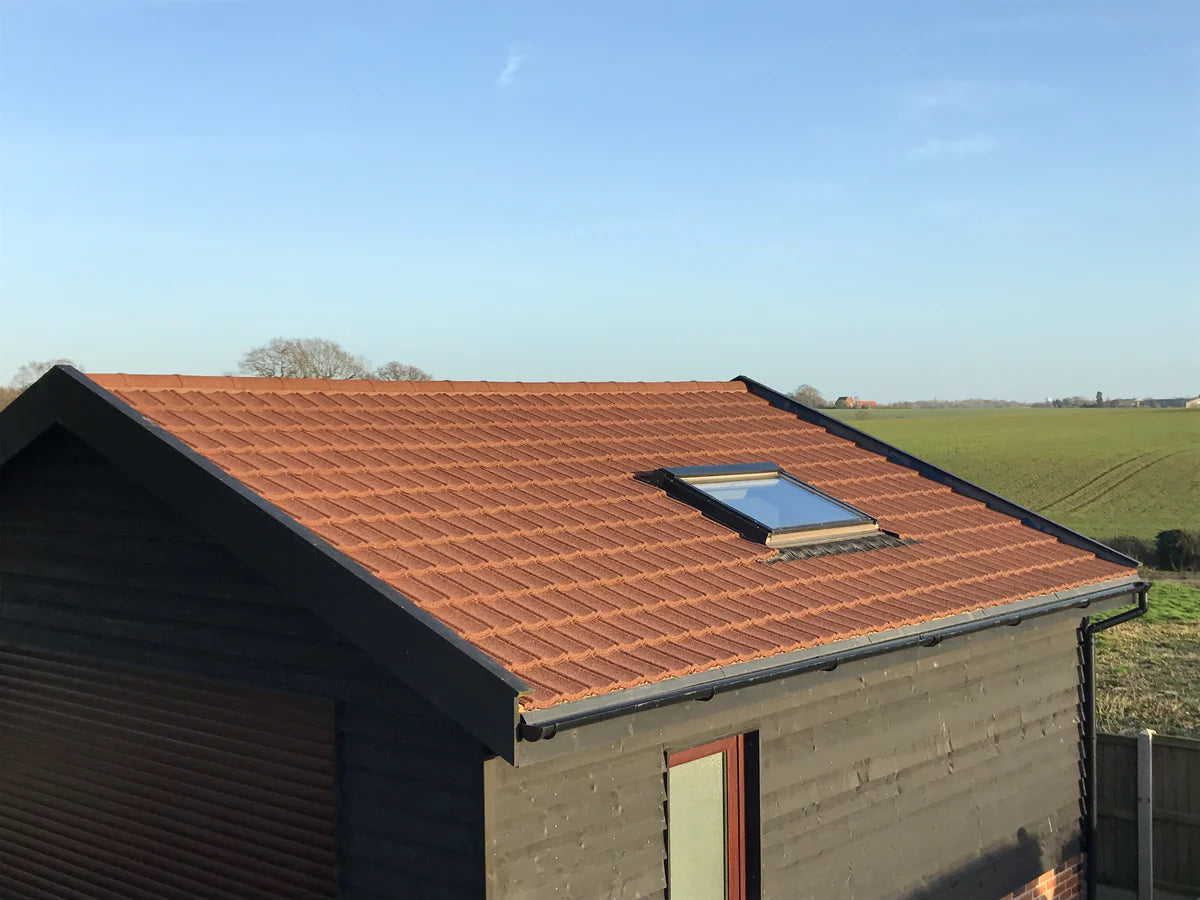 Roof with granulated brown Lightweight Tiles on a garage with a clear blue sky.