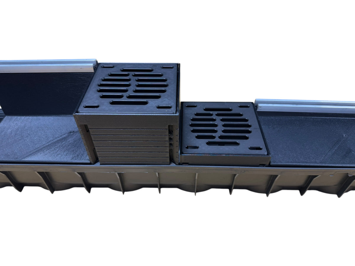 Black plastic troughs with slotted ends on a white background