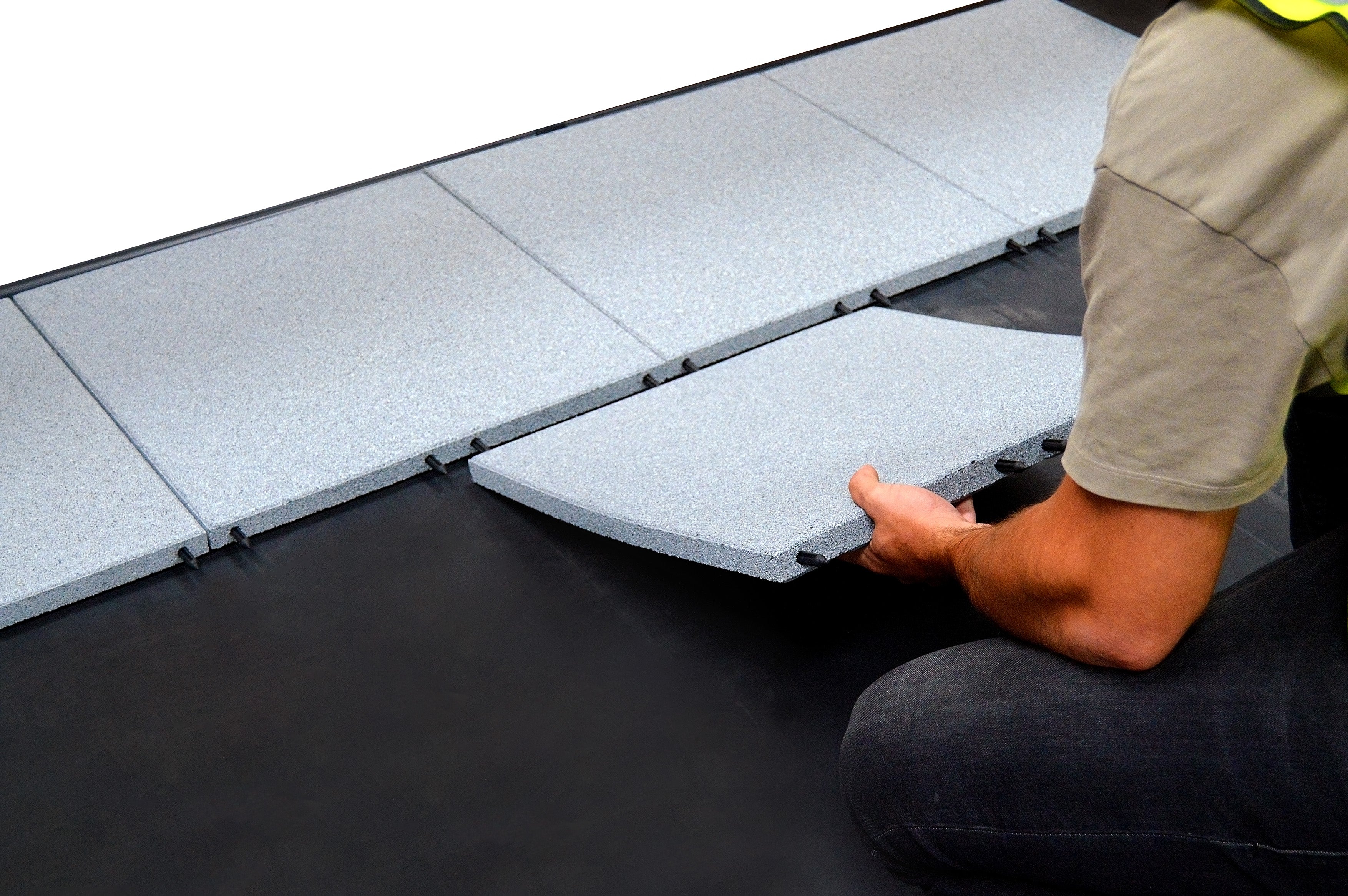 Installing a grey ecotred 500 tile using its interlocking pin system.