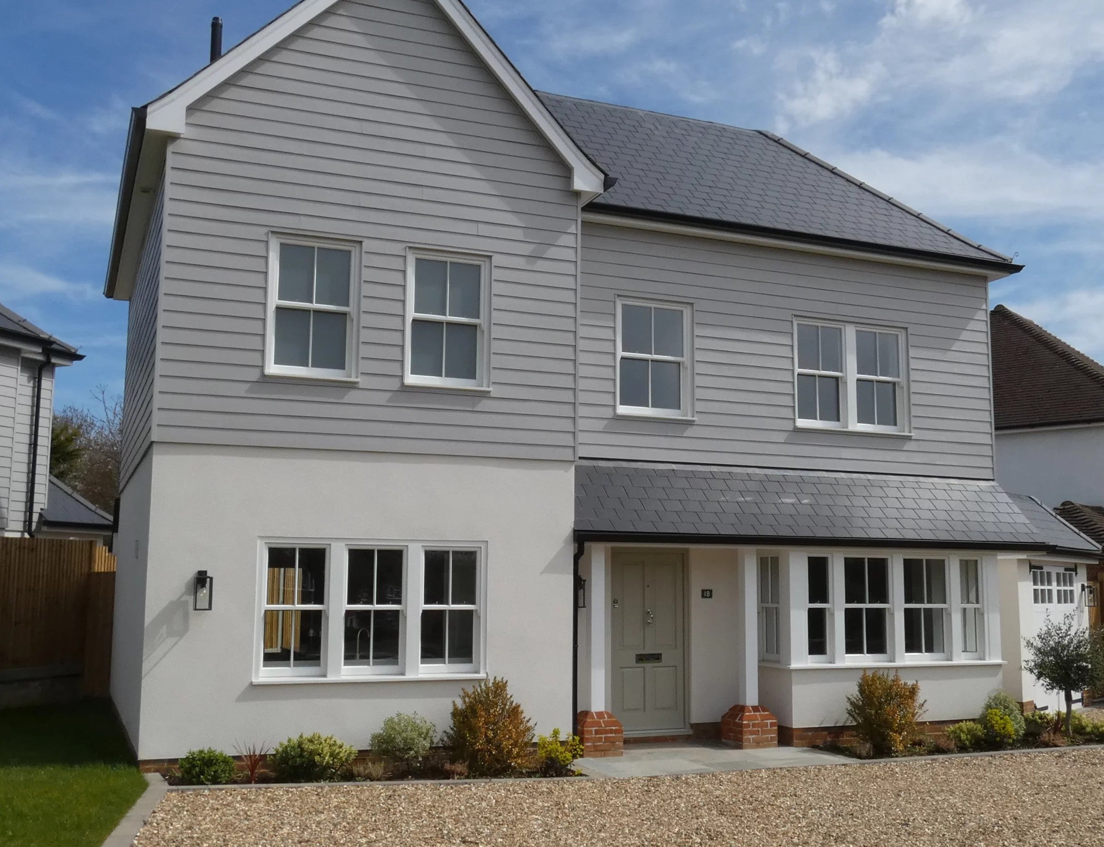 Two-story house with graphite fibre cement roof slates on a clear day.