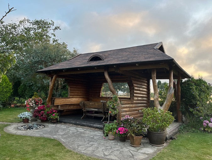 Wooden gazebo with outdoor furniture and plants in a garden setting