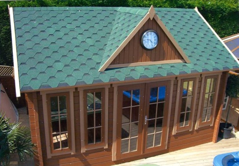Wooden cabin with a clock on its green roof, surrounded by greenery
