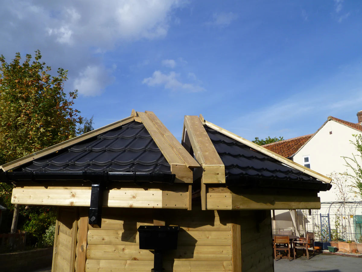 A close-up view of the smooth black lightweight roof tiles on a home observatory. The roof is split into two halves that can roll apart, with visible wooden framework supporting the tiled sections.