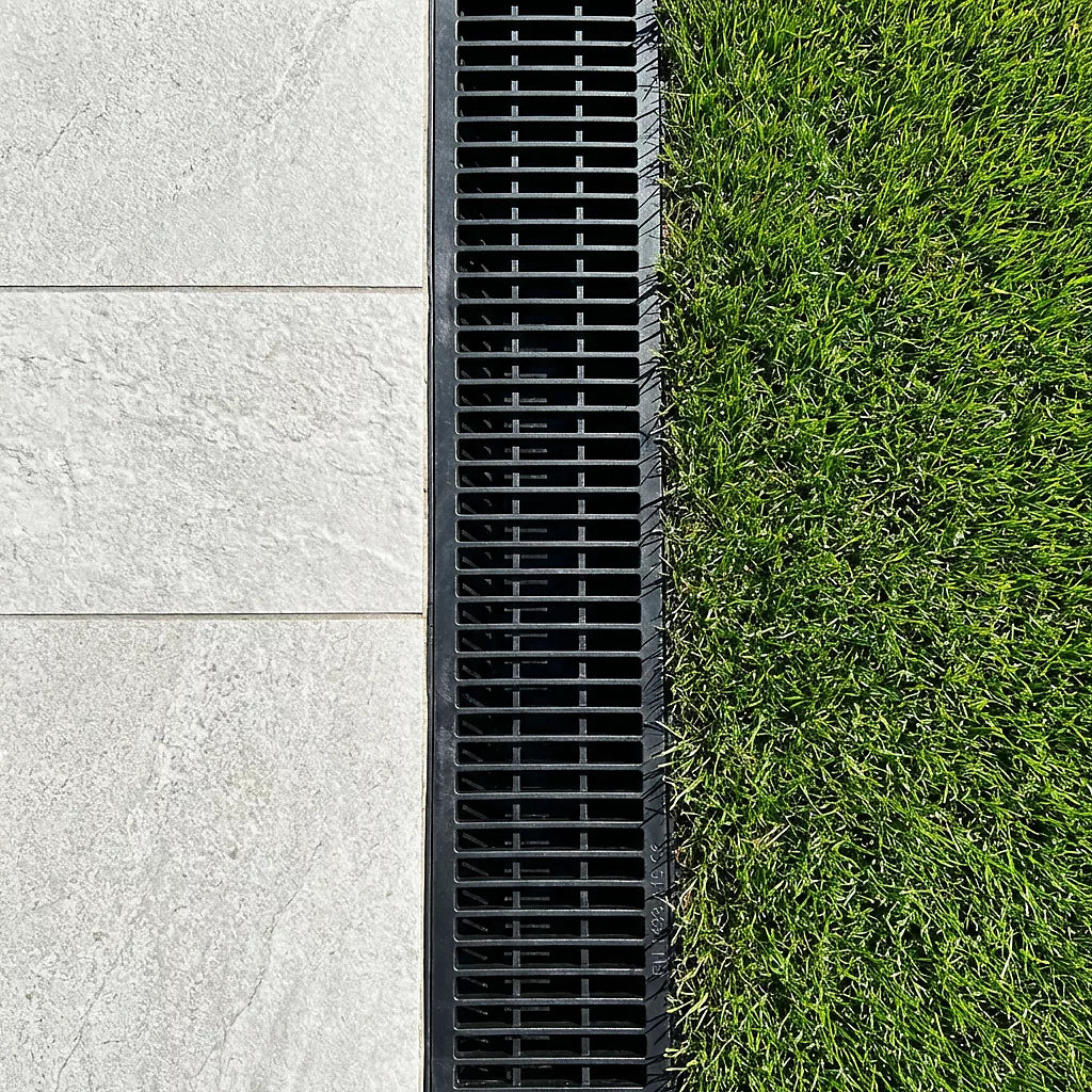 Black drain grate between a concrete pavement and grass